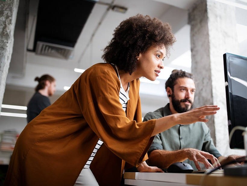 woman pointing at computer with man